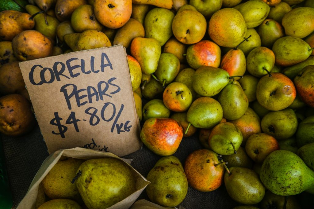 Close-up of Corella pears with price tag at a market, showcasing their fresh and juicy appeal.